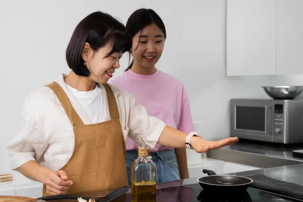 A mom and her daughter in the kitchen in front of the stove