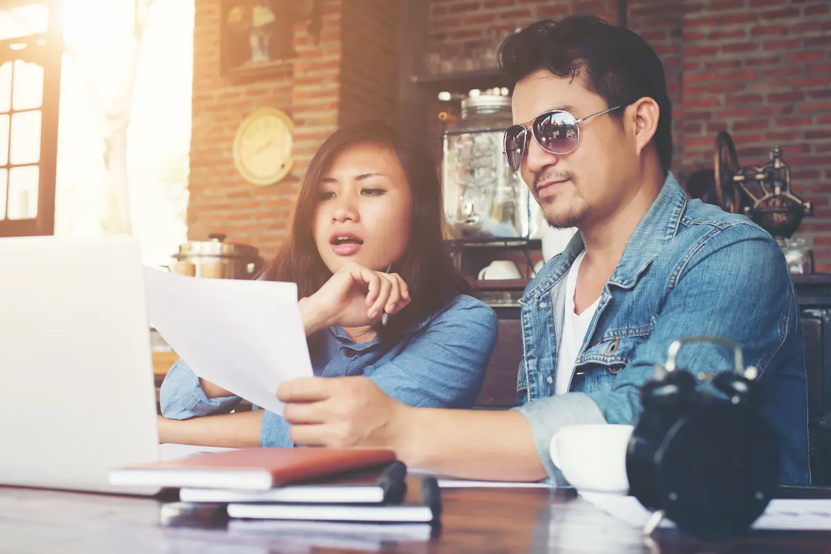 An Asian couple looking at their budget together while inside the house