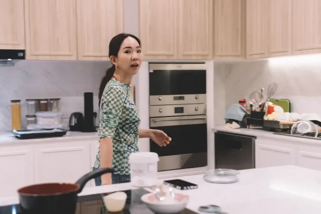 A mom in the kitchen is going to her cabinets at the back